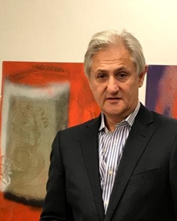 Ladislao Pío Ayerza, de traje oscuro, frente a dos cuadros abstractos en la oficina